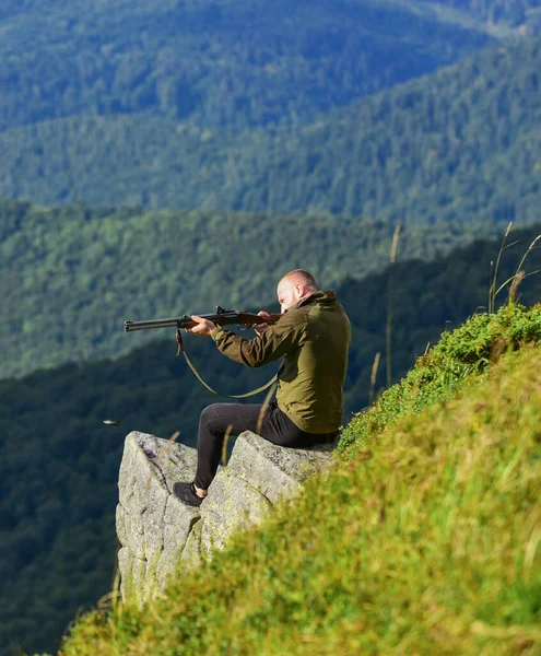 Hunter hold rifle. Hunter spend leisure hunting. Hunting in mountains. Man brutal gamekeeper nature landscape background. Hunting masculine hobby concept. Regulation of hunting. Focused on target — Stock Photo, Image