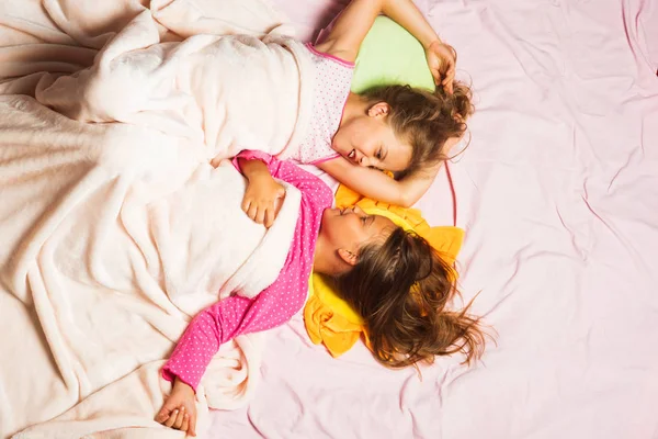 Kids in pink pajamas with messy hair covered with blanket — Stock Photo, Image