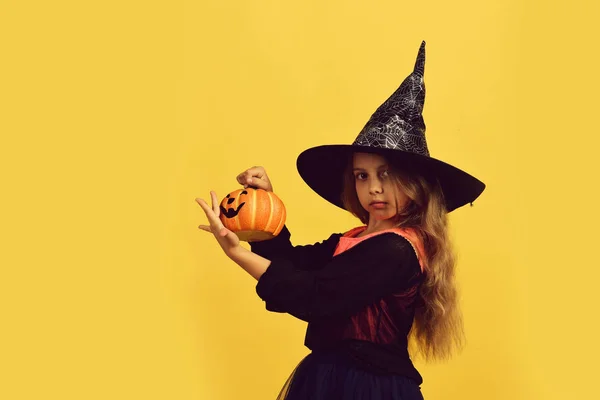 Girl with carved orange pumpkin isolated on warm yellow background — Stock Photo, Image
