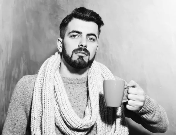 bearded man holding cup of tea, coffee with serious face