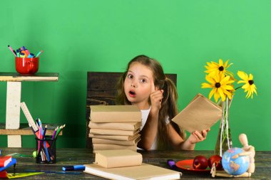 Kız öğrenci masada oturur renkli Kırtasiye, kitap, dünya ile
