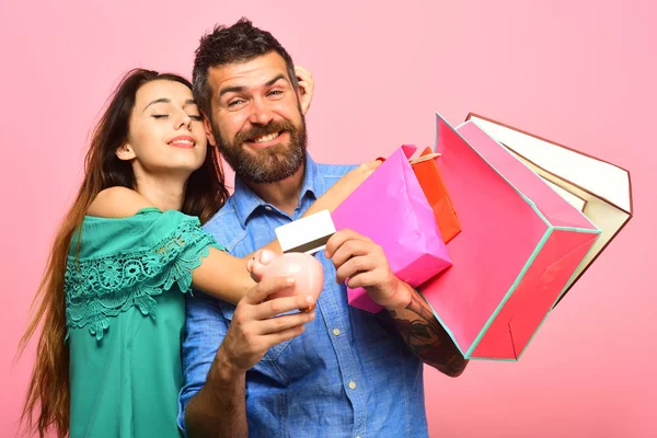 Man with beard holds credit card and piggy bank — Stock Photo, Image