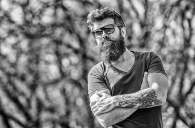 Güneş gözlüklü, sakallı, doğa geçmişi olan bir adam. Sakallı hippi vahşi adam koruyucu güneş gözlüğü takıyor. Hippi koyu güneş gözlüklerine güveniyor. Sakallı adam modern güneş gözlüğü takıyor. Uv filtresi