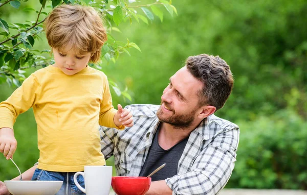 Healthy food and dieting. Childrens day. summer picnic. Morning breakfast. father and son eating outdoor. happy fathers day. Little boy with dad eat cereal. family dinner time. Happy to be a family — Stock Photo, Image