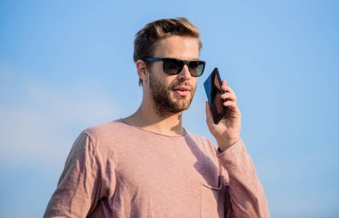 Online rezervasyon. Hayattaki modern teknoloji. Her zaman görüşüyoruz. Maço adam cep telefonu kullanıyor. Kendine güvenen bir adam telefonda konuşur. Arkadaşına seslen. Seksi erkek gökyüzü arka planı. Sıradan bir adam. Moda modeli