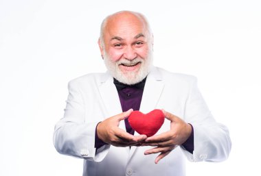 Sağlık hizmetleri. Kalp krizini önlüyor. Yaşlı kel sakallı adam elinde kırmızı oyuncak bir kalp tutuyor. Sağlıklı bir hayat. Sevgililer günü kalbi olan olgun bir adam. Kalp ve sağlık sigortası. Teşhis ve tedavi