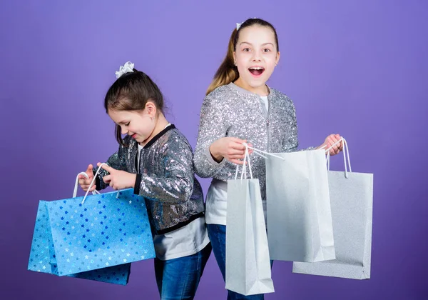 Alışveriş günü. Çocuk paketleri. Çocuk modası. Kız kardeş kız arkadaş, alışveriş torbaları, mor arka plan. Çünkü imaj her şeydir. Alışveriş ve satın alma. Kara Cuma. Satış ve indirim. — Stok fotoğraf