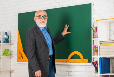 BTMM denekleri teknolojinin temelidir. Matematikte iyi ol. Sınıfta kök. Kıdemli öğretmen tahtada araç kullanır. Gözlüklü özel öğretmen. Okula dönüyorum. İletki cetvel. geometriyi kolayca öğren