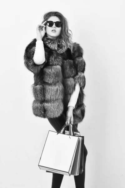 Buy with discount on black friday. Shopping or birthday gift. Woman shopping luxury boutique. Girl wear sunglasses and furry coat shopping white background. Lady hold shopping bags. Discount and sale — Stock Photo, Image