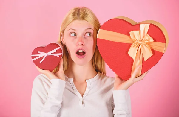Listen to your heart. Girl decide which gift she like more. Big surprise and small gift. Make choice. Romantic gift for her. Woman hold big and little heart shaped gift boxes. Which one she prefer