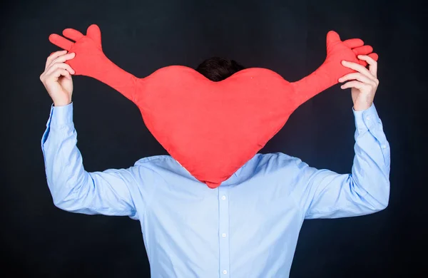 Hit in his heart by the emotion of love. Unhealthy man holding big red heart. Love sickness and heart problems. Having heart attack and heartache. Valentines man expressing love on 14 february