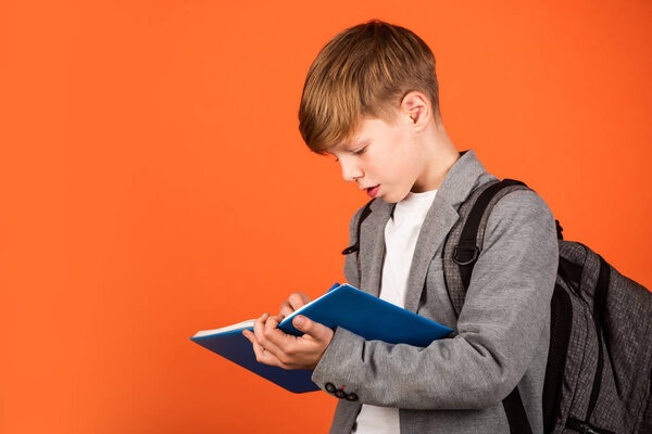 Enriching life with knowledge. Boy student brown background. Small student write in copy-book. Little student do homework assignment. Smart student back to school. Study and learn, copy space