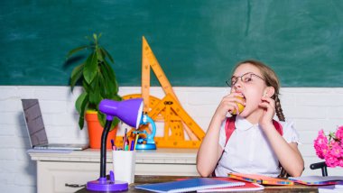 Vejetaryen diyeti. Sınıftaki küçük dahi çocuk. Öğle yemeği vakti. Modern teknolojiyle dijital çağ. Küçük kız elma yemeye hazır. Akıllı çocuk konsepti. Sağlıklı beslenme iyidir. Okula dönüyorum. Einstein