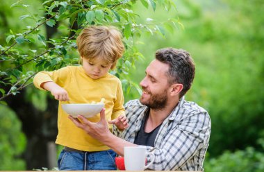 Çocuklar için menü. Aile ev yapımı yemeğin tadını çıkarır. Baba oğul yemek yer ve eğlenir. Beslenme alışkanlıkları. Küçük çocuk ve babası yemek yiyor. Çocuklar ve yetişkinler için besin. Sağlıklı beslenme konsepti. Bebeği besliyor.