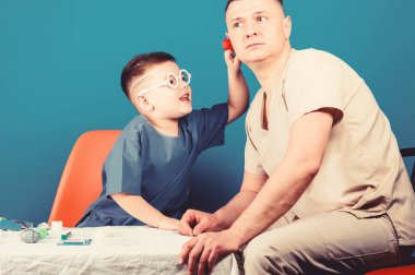Hastanede babası olan küçük bir çocuk. stetoskoplu baba ile mutlu çocuk. Aile doktoru. tıp ve sağlık. Baba ve oğlu tıbbi üniformalı. küçük çocuk babası ile oynamak. küçük çocuk doktor