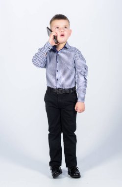 Küçük çocuk resmi kıyafetler cep telefonunu arıyor. Şirin çocuk akıllı telefonu tut. Gezici konuşma. Mobil iletişim. Modern bir alet. Küçük işadamı. İşletme. Yetiştirme ve geliştirme