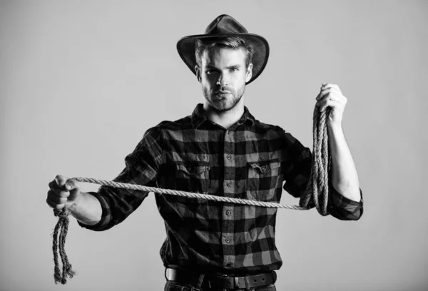 Lasso strumento di cowboy americano. Occupazioni in ranch. Lasso è utilizzato in rodei parte eventi competitivi. Il lazo può essere legato o avvolto. La vita occidentale. Uomo cowboy sfondo beige. Uomo che indossa cappello tenere corda — Foto Stock