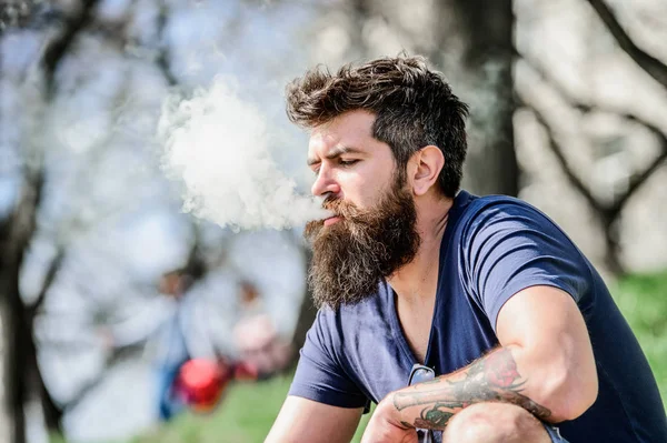 Hombre barba larga relajado con hábito de fumar. El hombre con barba y bigote exhala humo. Nubes blancas de humo aromatizado. Concepto de alivio del estrés. Hombre barbudo fumando vapor. Fumar cigarrillo electrónico —  Fotos de Stock