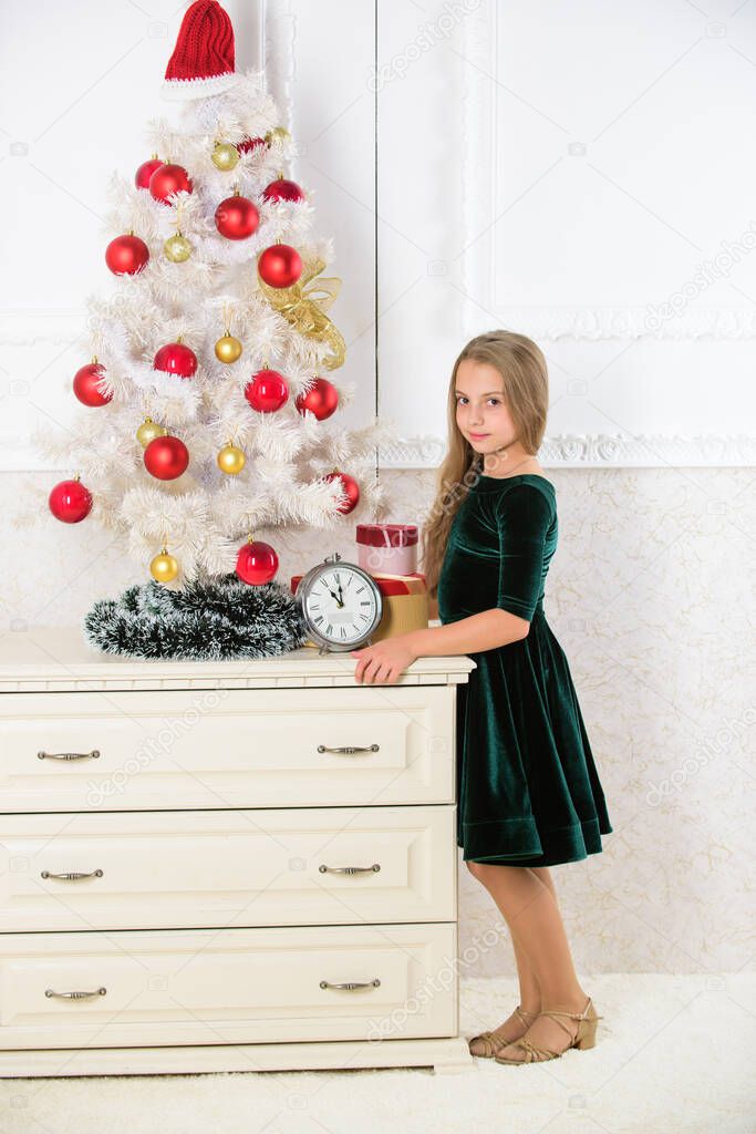 Get incredibly excited about christmas. Kid girl christmas tree waiting midnight clock. Childhood happiness concept. Child celebrate christmas at home. Favorite day of the year. Christmas celebration