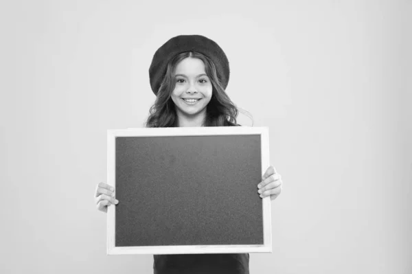 Little girl kid with backboard, copy space. board for announcement advertisement. back to school. school shopping sales. kid fashion. happy school girl in parisian beret. We can Serve you better — Stock Photo, Image