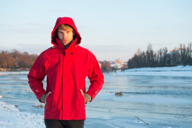 Noel tatili. İnsan ve doğa. Adam gün batımında karlı arazide yürüyor. seyahat ve keşif konsepti. Kırmızı parkalı adam. Kış erkek modası. Soğuk iklim için sıcak kıyafetler. Hava tahminleri