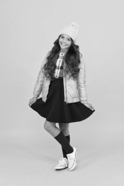 Mümkün olduğunca modaya uygun. Şık sonbahar görünüşlü mutlu bir kız. Havalı okul çocuğu gülüşü sarı arka plan. Moda tarzında küçük bir çocuk. Moda okuldaki gardıroba döndü.