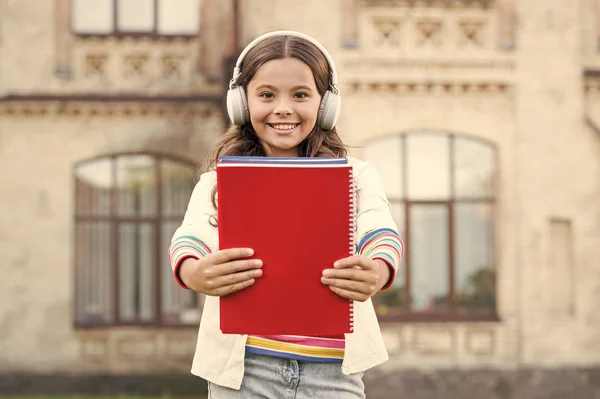 An awesome way of learning a language. Little girl learning English language with audio book. Happy small child listening to audio language course. Learn to speak a foreign language with confidence