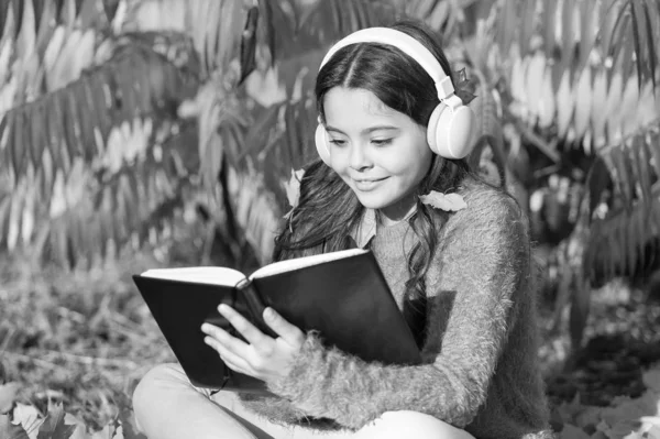 Kinder lesen gern. Zweimal schneller studieren mit visuellen und auditiven Informationen. Mädchen lesen Buch an einem Herbsttag. Kleine Kinder lernen gern im Herbstpark. Kinderstudie mit Buch. Herbstliches Literaturkonzept — Stockfoto