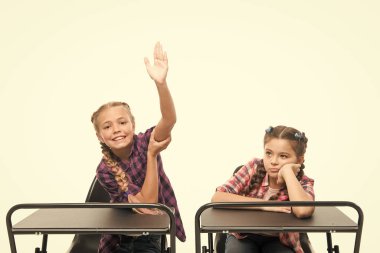 Çalışma sürecinin keyfini çıkarın. Öğrenciler sınıf arkadaşları masa başında. Okula geri dön. Özel okul konsepti. İlkokul eğitimi. Küçük kızlar okul arkadaşları birlikte çalışır. Cevap vermek için el kaldırın