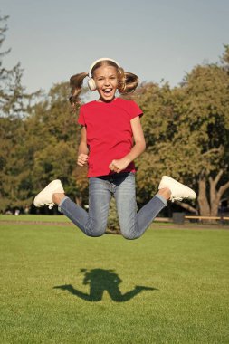 Stereo kulaklıklar. Modern teknolojiyi kullanan bir çocuk. Modern çocuk. Mükemmel yüksek ses. Hiç bitmeyen neşe. Kız müzik modern gadget dinleme. Çocuk kablosuz kulaklık dans atlama ile mutlu