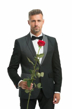 Gül çiçekli smokin giyen adam. Sevgililer günün kutlu olsun. Özel bir gün. Erkek resmi giyim tarzı. Romantik bir randevuda şık takım elbiseli ve kravatlı seksi bir adam. Akşam etkinlikleri için siyah kravat kuralı