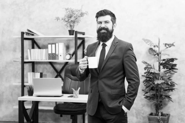 Homem barbudo empresário segurar copo de café stand fundo do escritório. Beber café pausa relaxante. O chefe gosta de bebidas energéticas. Comece o dia com café. Pessoas de sucesso bebem café. Viciado em cafeína — Fotografia de Stock