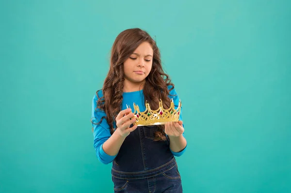Real values. Kid hold golden crown symbol of princess. Girl cute baby looking at crown turquoise background. Become princess concept. Every girl dreaming to be princess. Lady little princess