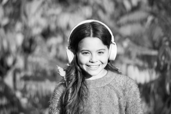 她热爱自然和音乐。上课时间。心情不好小女孩听有声读物。戴耳机的快乐的孩子。网上教育。儿童电子书。好好享受秋天吧。公园散步的好日子 — 图库照片