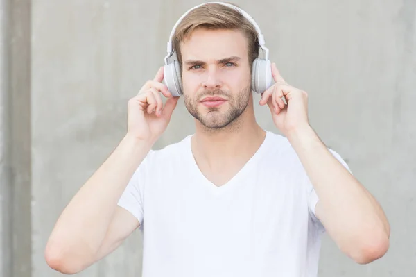 A technológia megváltoztatta a zenét. Jóképű férfi szürke fülhallgatót visel. Borotválatlan srác zenét hallgat. Új technológia. Sztereó hangtechnika. Modern zenei technológia. Modern élet — Stock Fotó