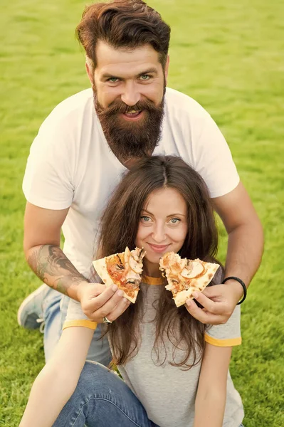 En sevdiğin de bu. Fast food. Sakallı adam kadın sevimsiz pizza besliyor. Açık havada flört aşık çift pizza yemek. Aç öğrenciler yemek paylaşıyor. Çimenlikte dinlendirici pizza yiyen çift. Aile hafta sonu — Stok fotoğraf