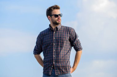 Mükemmel görüş. Göz sağlığı. Modaya uygun güneş gözlükleri. Ultraviyole koruma kavramı. Erkek gözlüklü model açık havada mavi gökyüzü arka planı. Yakışıklı adam güneş gözlüğü takıyor. Moda gözlüklü hippi.