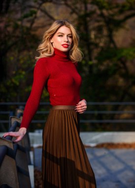 Beni takip edin. Haidresser ve makyaj. Sonbahar moda sezonu. Sonbahar kadını dışarıda kıvırcık saçlı. Etek ve süveter giyen kız. Pileli trend. Uzun sarı saçlı kız şehir yürüyüşü. dişi güzellik