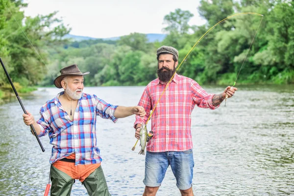 Dos pescador feliz con caña de pescar y red. turismo de caza. padre e hijo pescando. Acampar en la orilla del lago. Pesca de caza mayor. amistad. concepto de una escapada rural. hobby. Tiempo de pesca con mosca — Foto de Stock