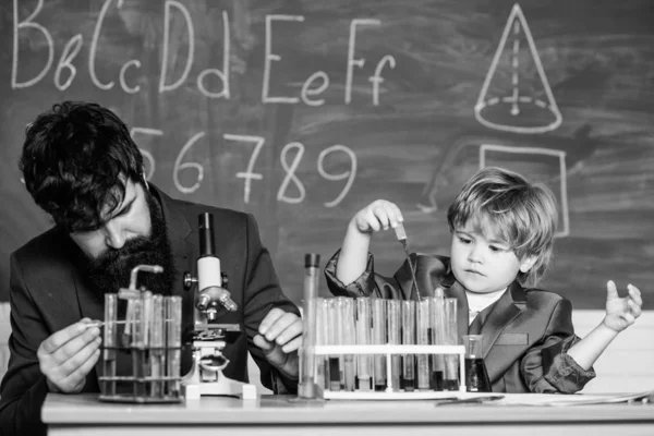 Η γνώση είναι νόστιμη. σχολείο επιστήμονας που σπουδάζει επιστήμη. δάσκαλος με το αγοράκι. Πίσω στο σχολείο. πατέρας και γιος στο σχολείο. Μικρό παιδί μαθαίνοντας χημεία στο σχολικό εργαστήριο — Φωτογραφία Αρχείου