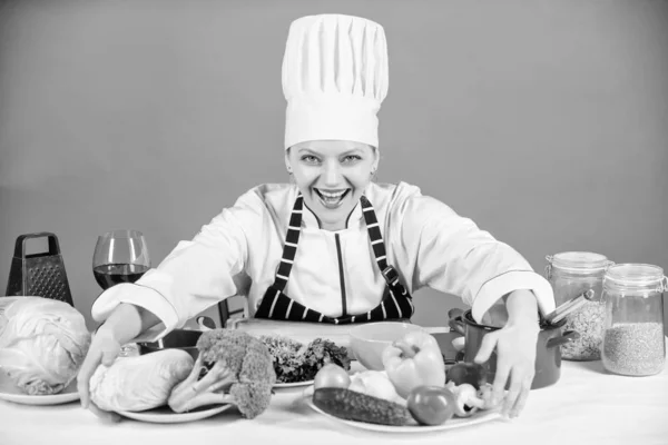 Woman chef cooking healthy food. Gourmet main dish recipes. Delicious recipe concept. Girl in hat and apron. Cooking healthy food. Fresh vegetables ingredients for cooking meal. Lets start cooking