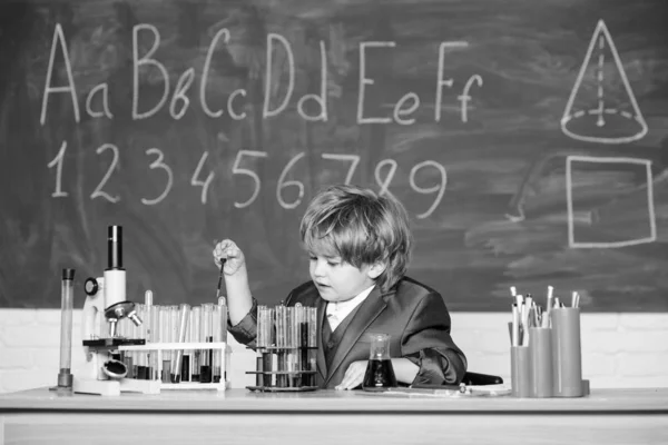 Knowledge day. Basic knowledge primary school education. Happy childhood. Child enjoy studying. Knowledge concept. Boy near microscope and test tubes in school classroom. Kid study biology chemistry