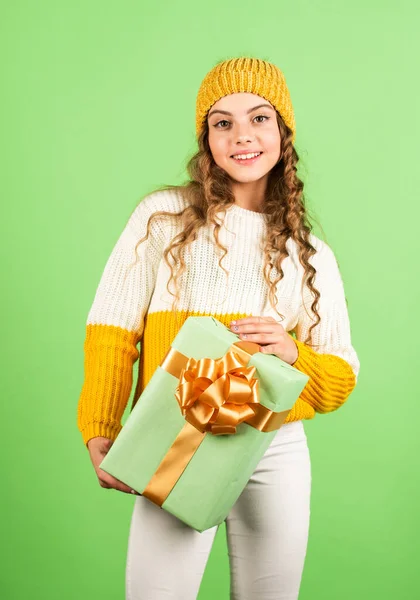 Se acerca la Navidad. niño mantenga la caja actual fondo verde. Feliz año nuevo. regalo de Navidad venta de compras. Feliz navidad para ti. descuentos de vacaciones de invierno. alegre niña tejida sombrero y suéter —  Fotos de Stock