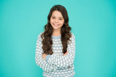 Daha güzel görün. Güzel ve mutlu çocuk mavi arka plana bak. Uzun dalgalı saçlı, moda görünümlü küçük bir kız. Şirin bir manken. Vogue bakışı. Moda ve güzellik. Kuaför salonu.