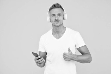 İyi bir şarkı dinle. Guy modern kullanıcı mobil uygulaması. Favori müzik listesi. Müzik aboneliği. Olgun adam müzik dinler modern kulaklıklar ve akıllı telefonlar. Dinleme konsepti. En iyi müzik uygulamaları