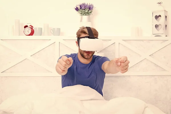 The game is on. Game developer or gamer. Handsome guy wearing VR goggles for video game. Caucasian man with virtual reality headset enjoy playing pc game in bed