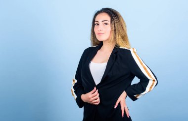 Zarif ve atletik parçaları karıştırıyorum. Spor kıyafetleri podyumlarda kural koyuyor. Voluminous kıvrımlı saç stili. Moda kıvrımlı saç stili. Şık spor. Mavi arka planda, gülümseyen yüz stili saç stili