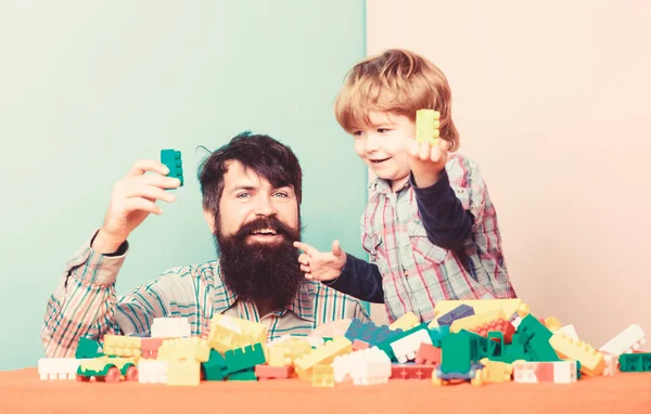 Papa en Kid bouwen van kunststof blokken. Vader en zoon creëren kleurrijke constructies met bakstenen. Ontwikkeling van kinderopvang en opvoeding. Bearded vader en jongen spelen samen. Vader zoon spel spelen — Stockfoto