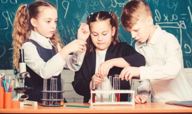 Okulda kimya öğrenen küçük çocuklar. Öğrenciler mikroskopla biyoloji deneyleri yapıyor. Çocuklar Günü 'nde. Kimya. Okula dönelim. Okuldaki küçük çocuklar. Kendine güvenen eczacı.