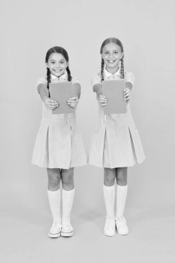 Okul kütüphanesi. Evde eğitim konsepti. Okuryazarlık kulübü. Sarı arka plan üzerine kitaplar tutan sevimli çocuklar. Ansiklopedisi ya da çocuk kitapları olan küçük kızlar. Okullar için eğitim kitapları. Kitap okuma